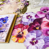 victorian pansy themed letterbox gift set with floral pouch, botanical stickers, vellum journaling sheets and antique style metal and glass bookmark in shades of purple, yellow and blue
