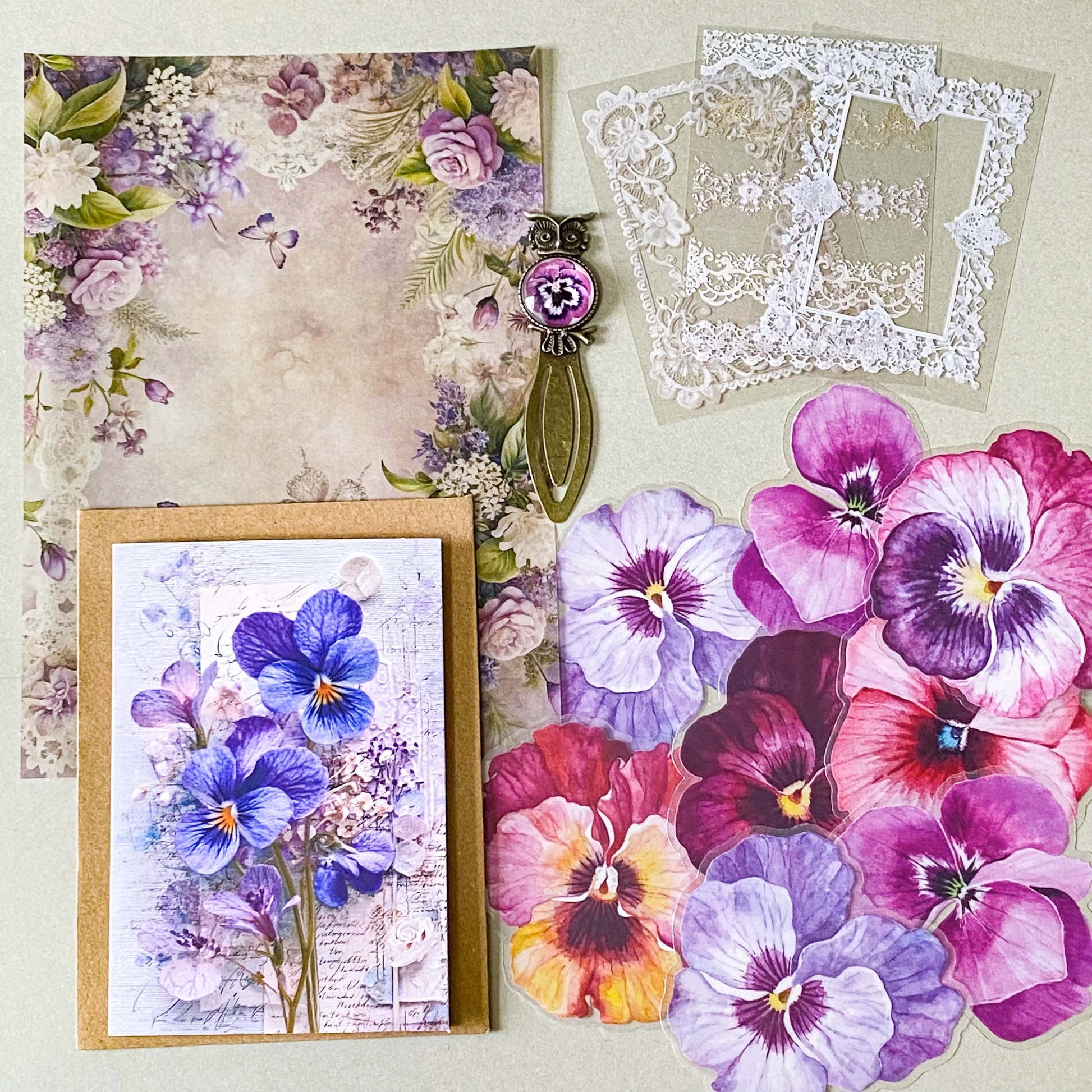 victorian pansy themed letterbox gift set with floral pouch, botanical stickers, vellum journaling sheets and antique style metal and glass bookmark in shades of purple, yellow and blue
