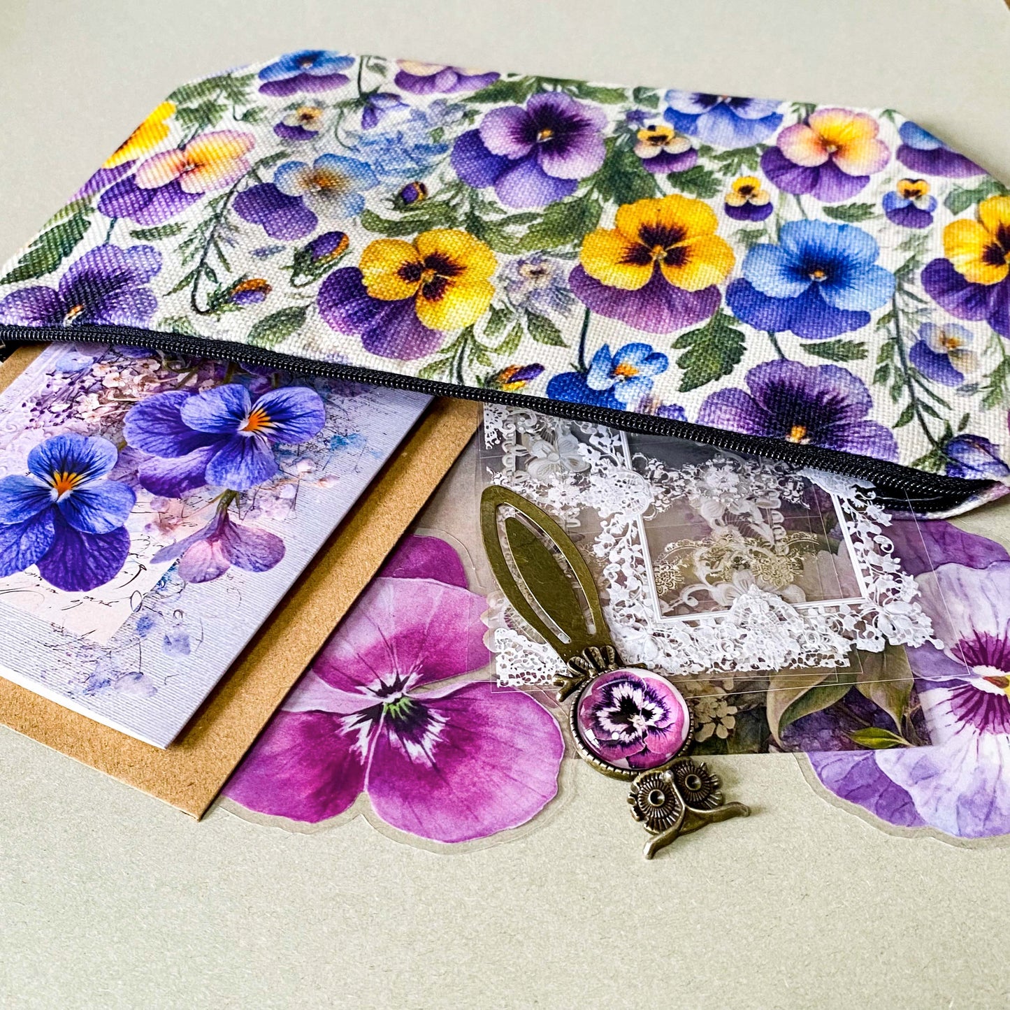 victorian pansy themed letterbox gift set with floral pouch, botanical stickers, vellum journaling sheets and antique style metal and glass bookmark in shades of purple, yellow and blue
