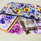 victorian pansy themed letterbox gift set with floral pouch, botanical stickers, vellum journaling sheets and antique style metal and glass bookmark in shades of purple, yellow and blue