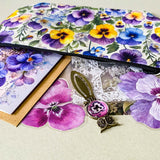 victorian pansy themed letterbox gift set with floral pouch, botanical stickers, vellum journaling sheets and antique style metal and glass bookmark in shades of purple, yellow and blue