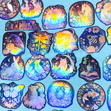 Collection of colorful, iridescent stickers with various designs on a blue background