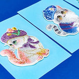 Two embroidered applique cat patches with colorful hats on a blue background