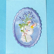 blue embroidered applique patch of a white bunny rabbit with blue flowers in an oval shape