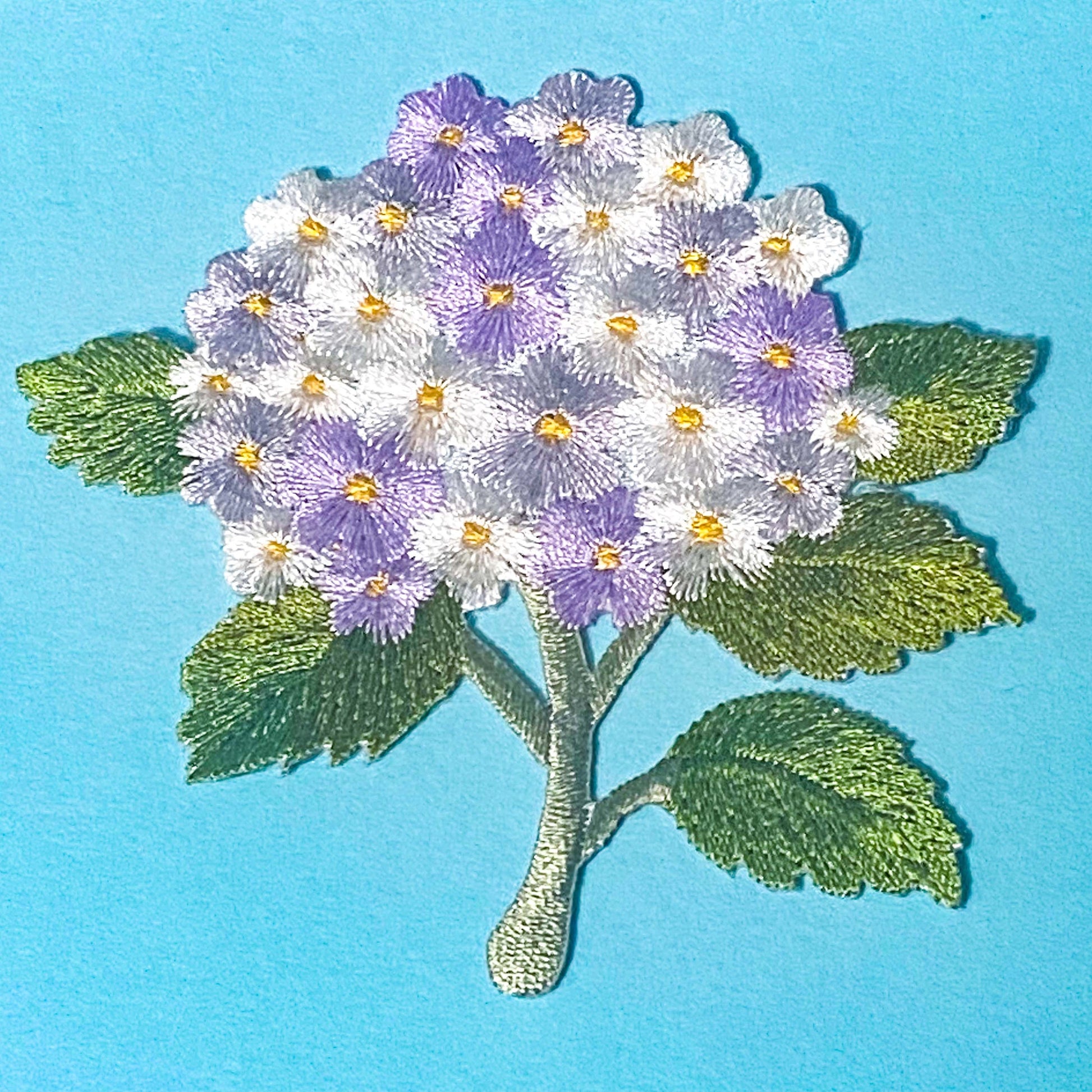 iron on embroidery patch of a lilac and white hydrangea on a blue background
