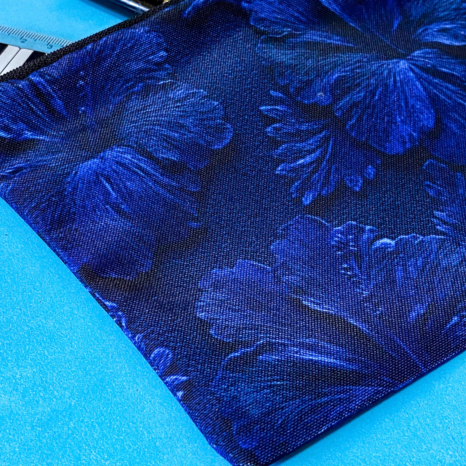 very dark inky blue canvas zip pouch with floral hibiscus deep design on both sides. Midnight botanical design with leaves and petals. floral gifts uk.