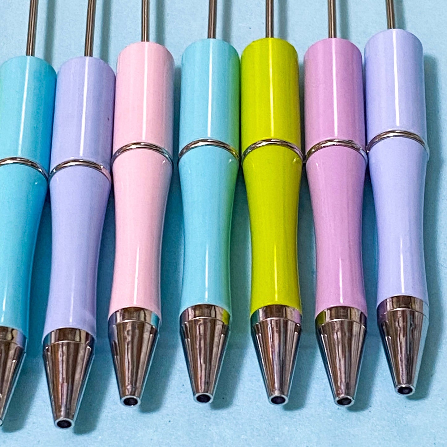 Set of colourful pastel coloured pen blanks with metallic tips on a blue background