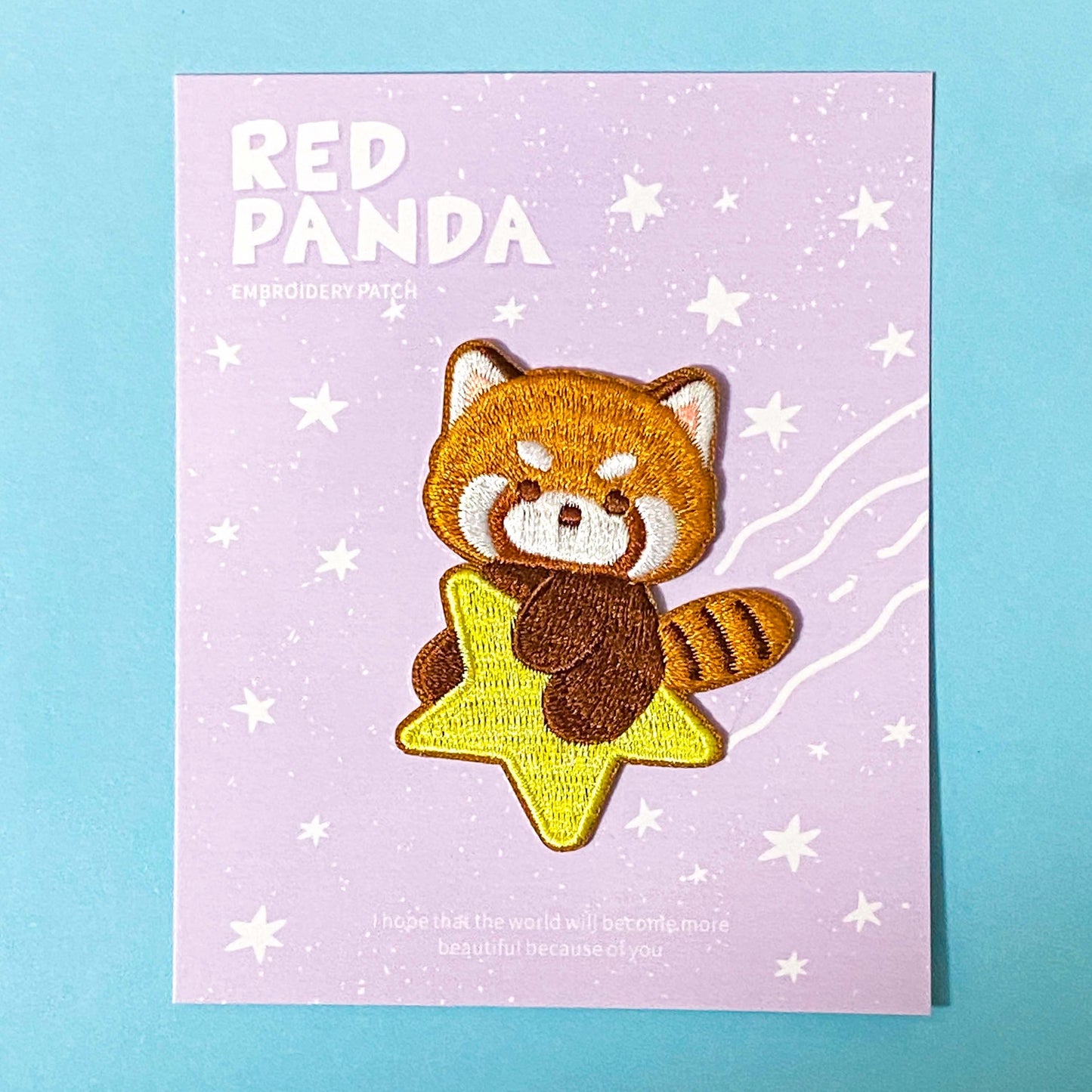 Red panda patch on a purple card with star patterns against a blue background