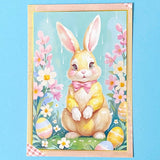 postcard of a pastel coloured bunny with flowers and Easter eggs on a blue background