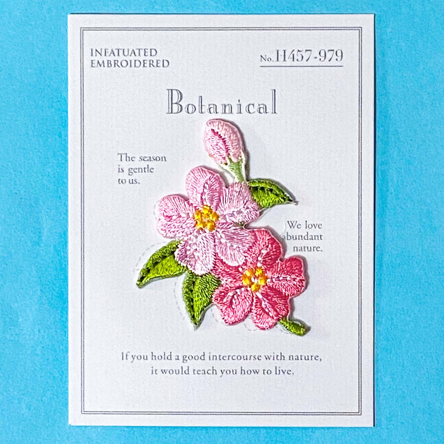 pink apple blossom flower embroidery iron on patch on a blue background