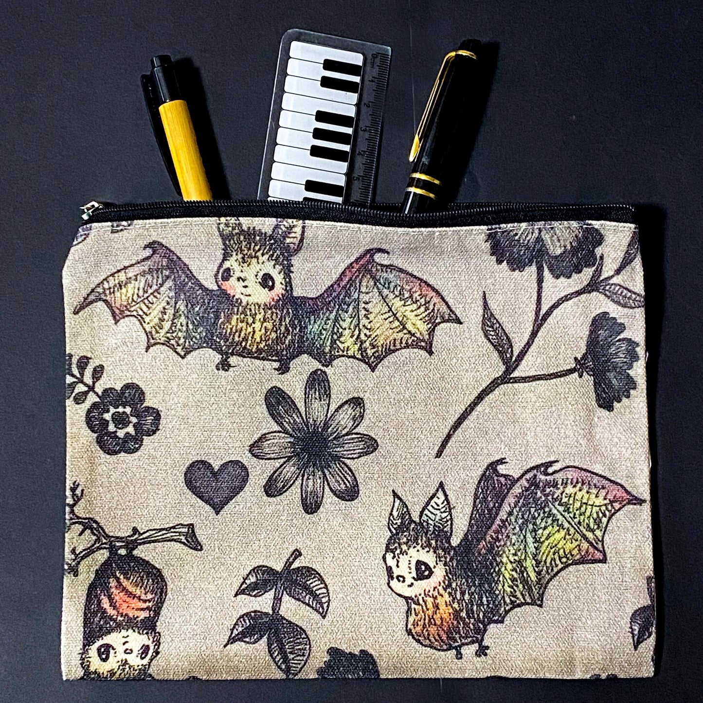 canvas taupe brown zip pouch featuring dark rainbow coloured flying bats and botanical illustrations, presented with kraft belly band and wax seal sticker. uk letterbox gifts shop.