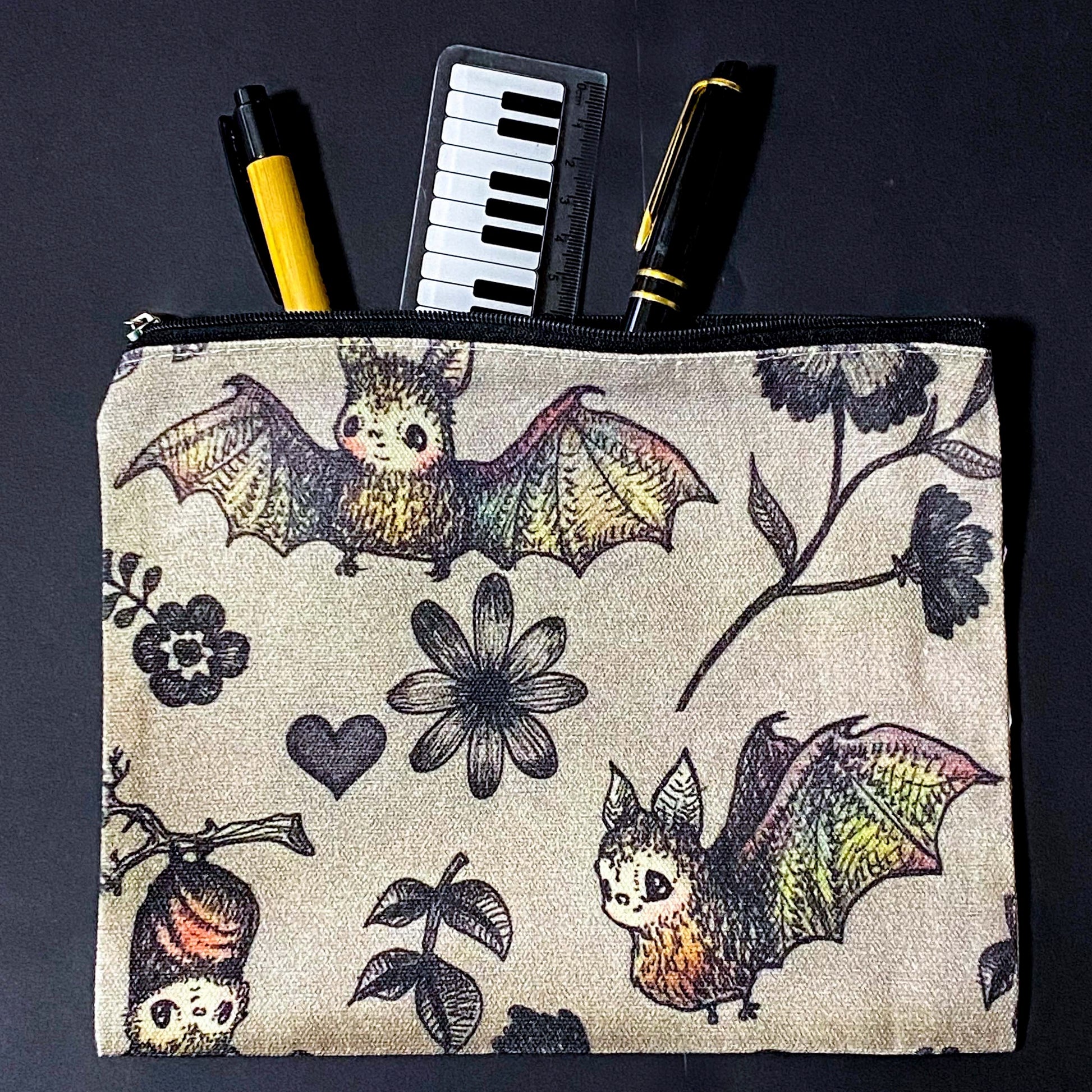 canvas taupe brown zip pouch featuring dark rainbow coloured flying bats and botanical illustrations, presented with kraft belly band and wax seal sticker. uk letterbox gifts shop.