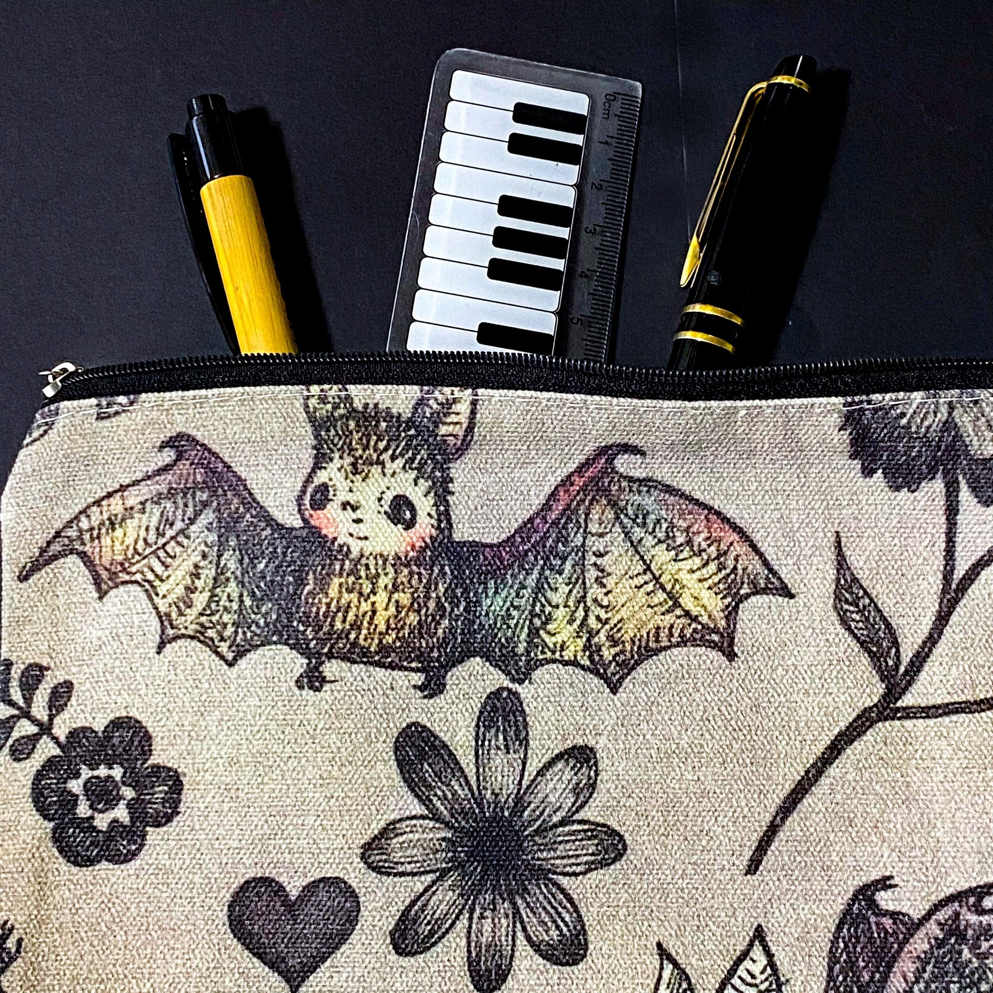 canvas taupe brown zip pouch featuring dark rainbow coloured flying bats and botanical illustrations, presented with kraft belly band and wax seal sticker. uk letterbox gifts shop.