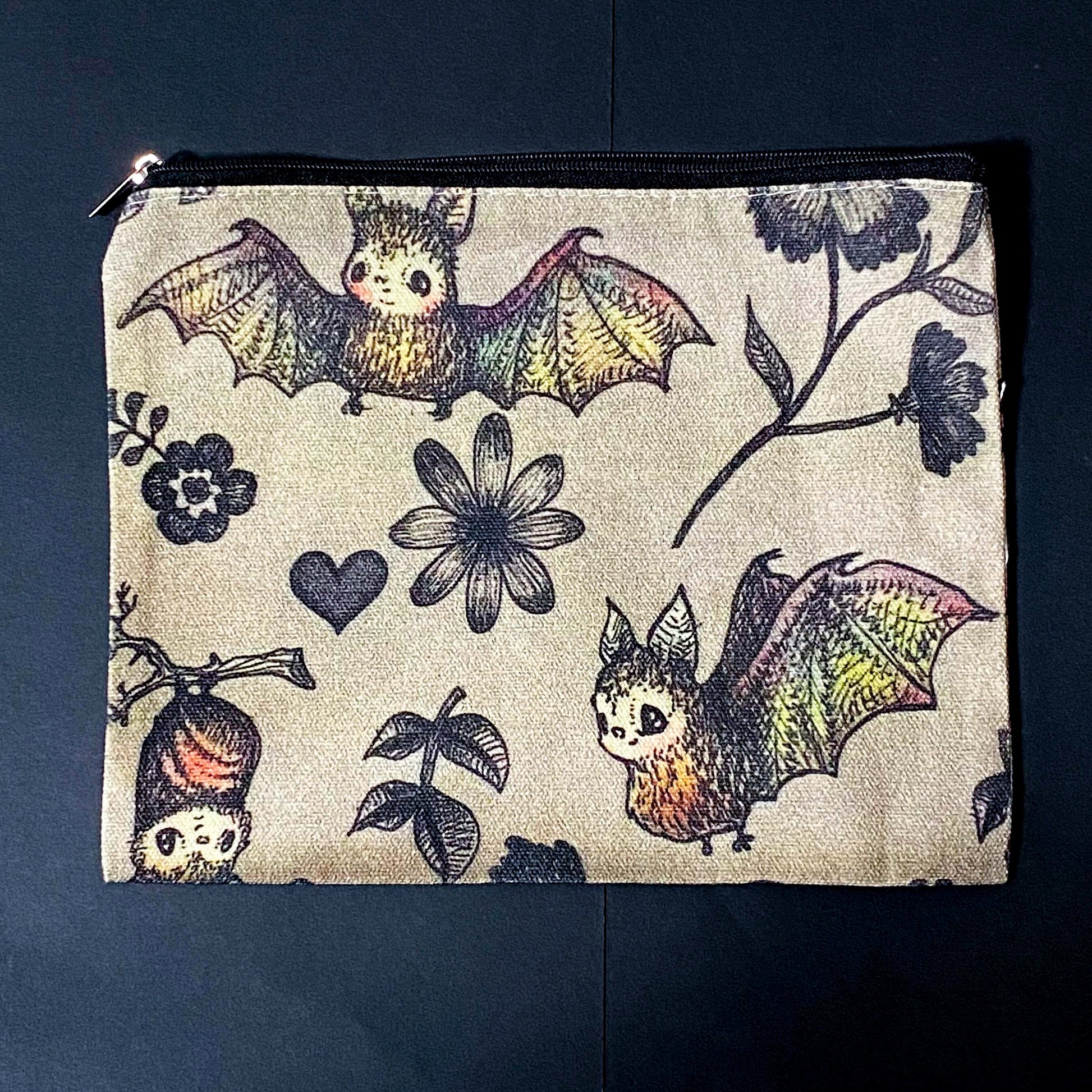 canvas taupe brown zip pouch featuring dark rainbow coloured flying bats and botanical illustrations, presented with kraft belly band and wax seal sticker. uk letterbox gifts shop.