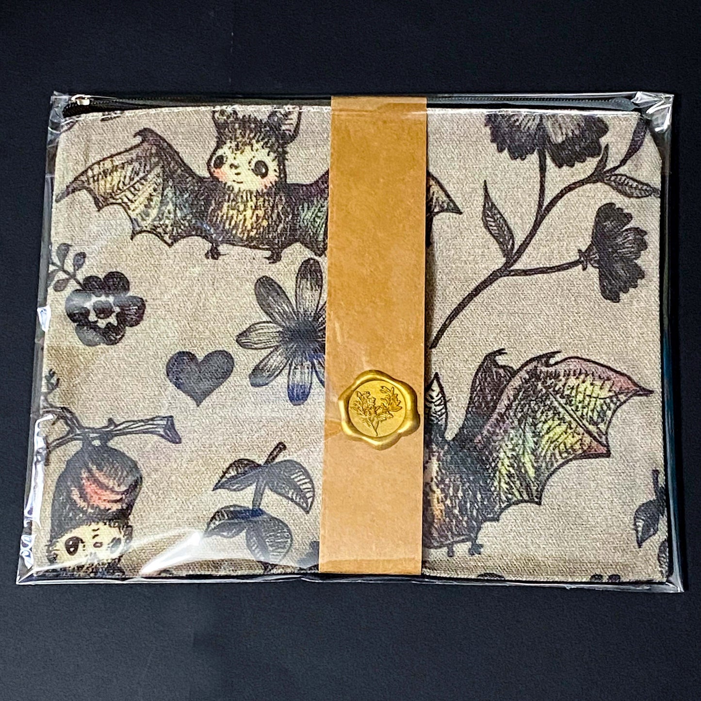 canvas taupe brown zip pouch featuring dark rainbow coloured flying bats and botanical illustrations, presented with kraft belly band and wax seal sticker. uk letterbox gifts shop.