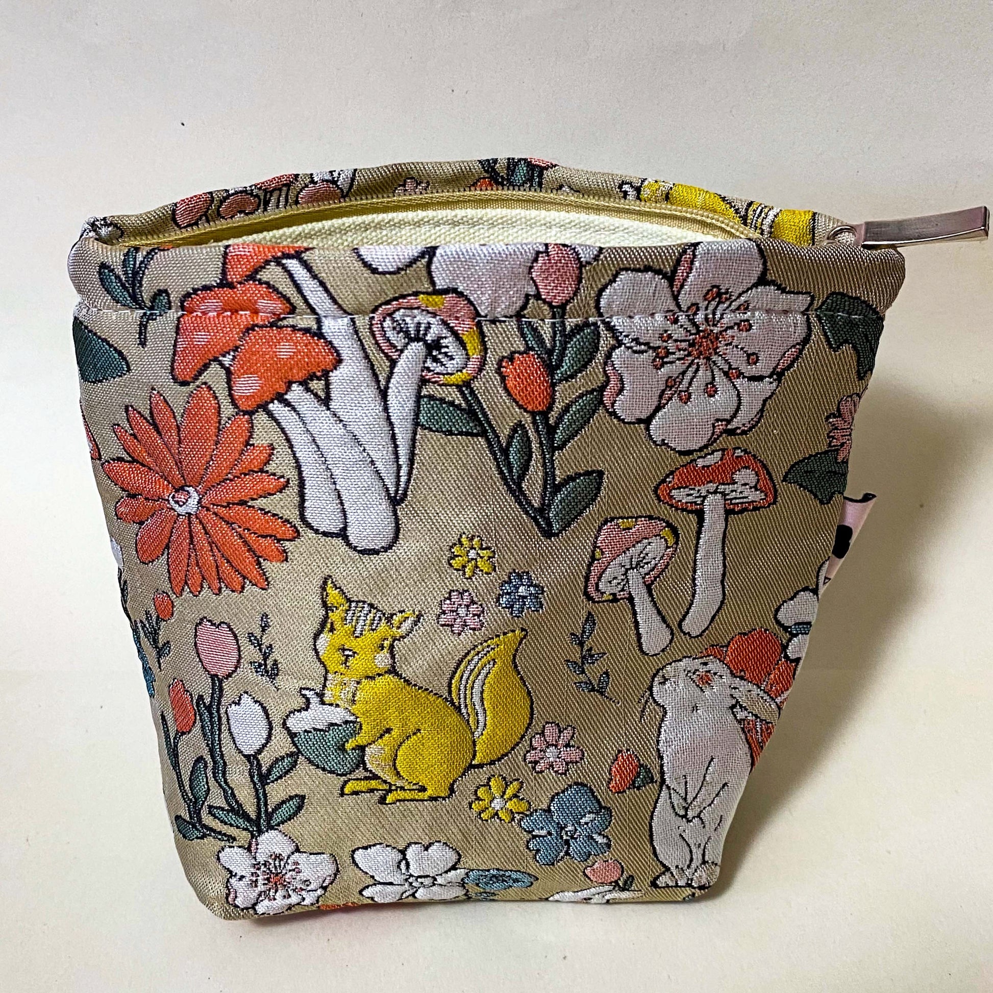 premium woven woodland cosmetic pouch featuring a squirrel, rabbit and wild flowers. Cream lining, bucket shape and concealed zip. Uk premium letterbox gifts. Make up bag or jewellery pouch.