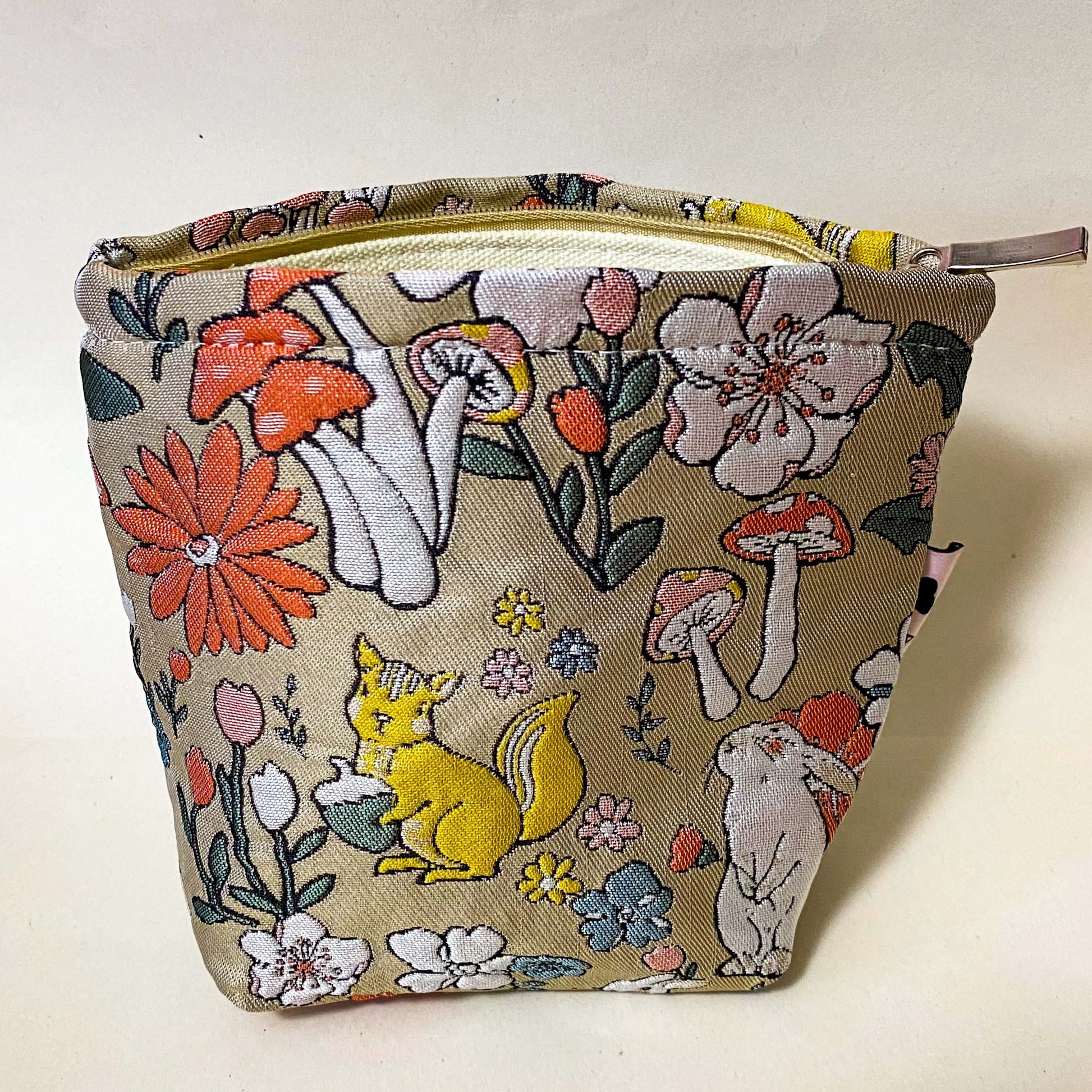 premium woven woodland cosmetic pouch featuring a squirrel, rabbit and wild flowers. Cream lining, bucket shape and concealed zip. Uk premium letterbox gifts. Make up bag or jewellery pouch.