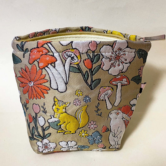premium woven woodland cosmetic pouch featuring a squirrel, rabbit and wild flowers. Cream lining, bucket shape and concealed zip. Uk premium letterbox gifts. Make up bag or jewellery pouch.