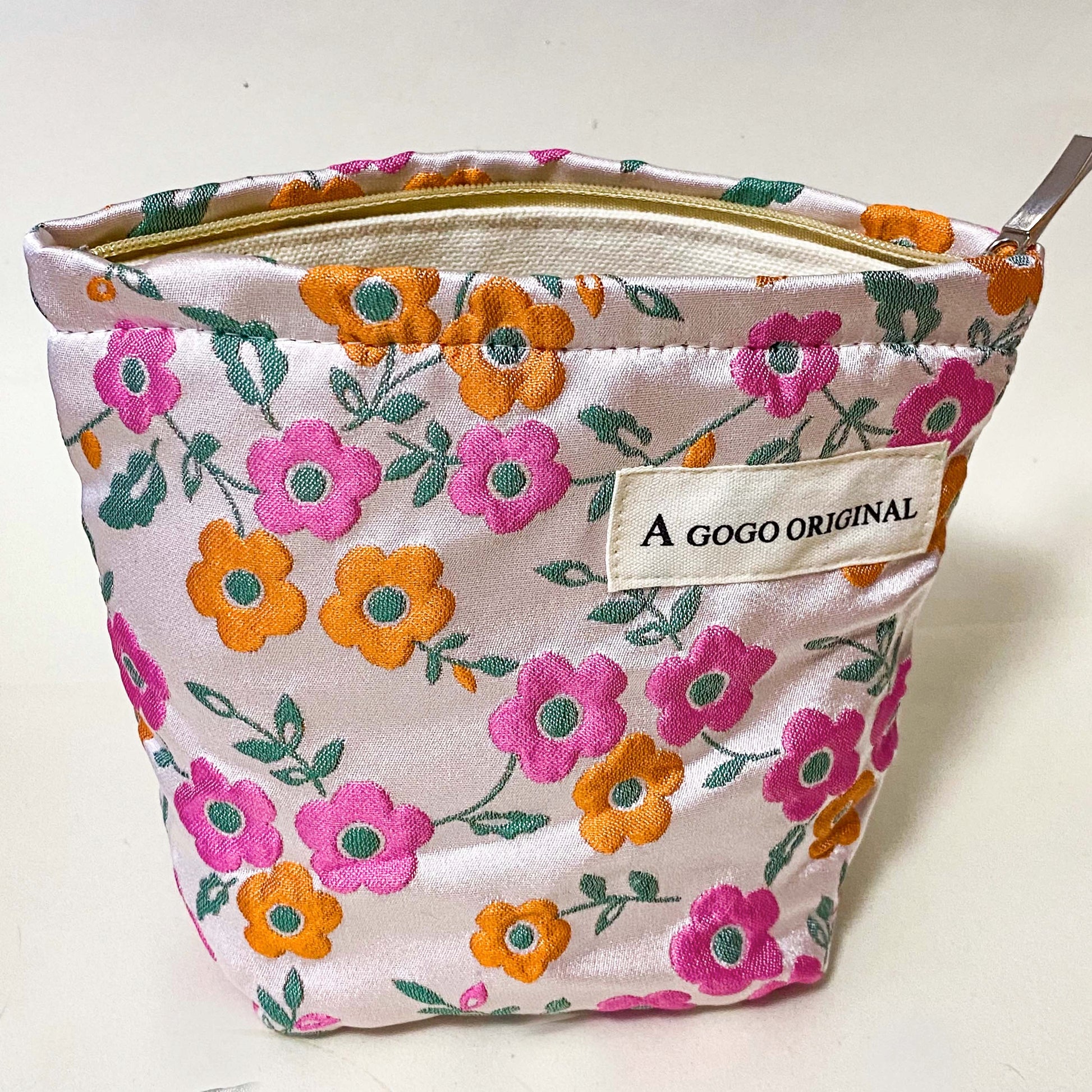 premium woven retro blossom lane cosmetic pouch with pink and coral orange floral design, cream lining and concealed zip. Small bucket shape make up bag. uk letterbox gifts for flower lovers.