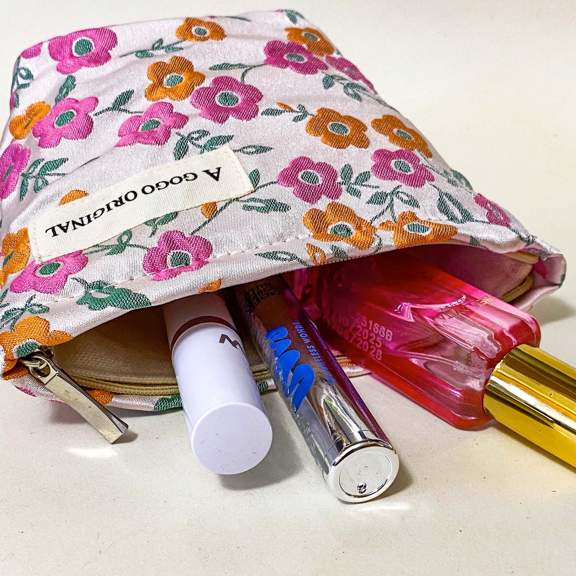 premium woven retro blossom lane cosmetic pouch with pink and coral orange floral design, cream lining and concealed zip. Small bucket shape make up bag. uk letterbox gifts for flower lovers.
