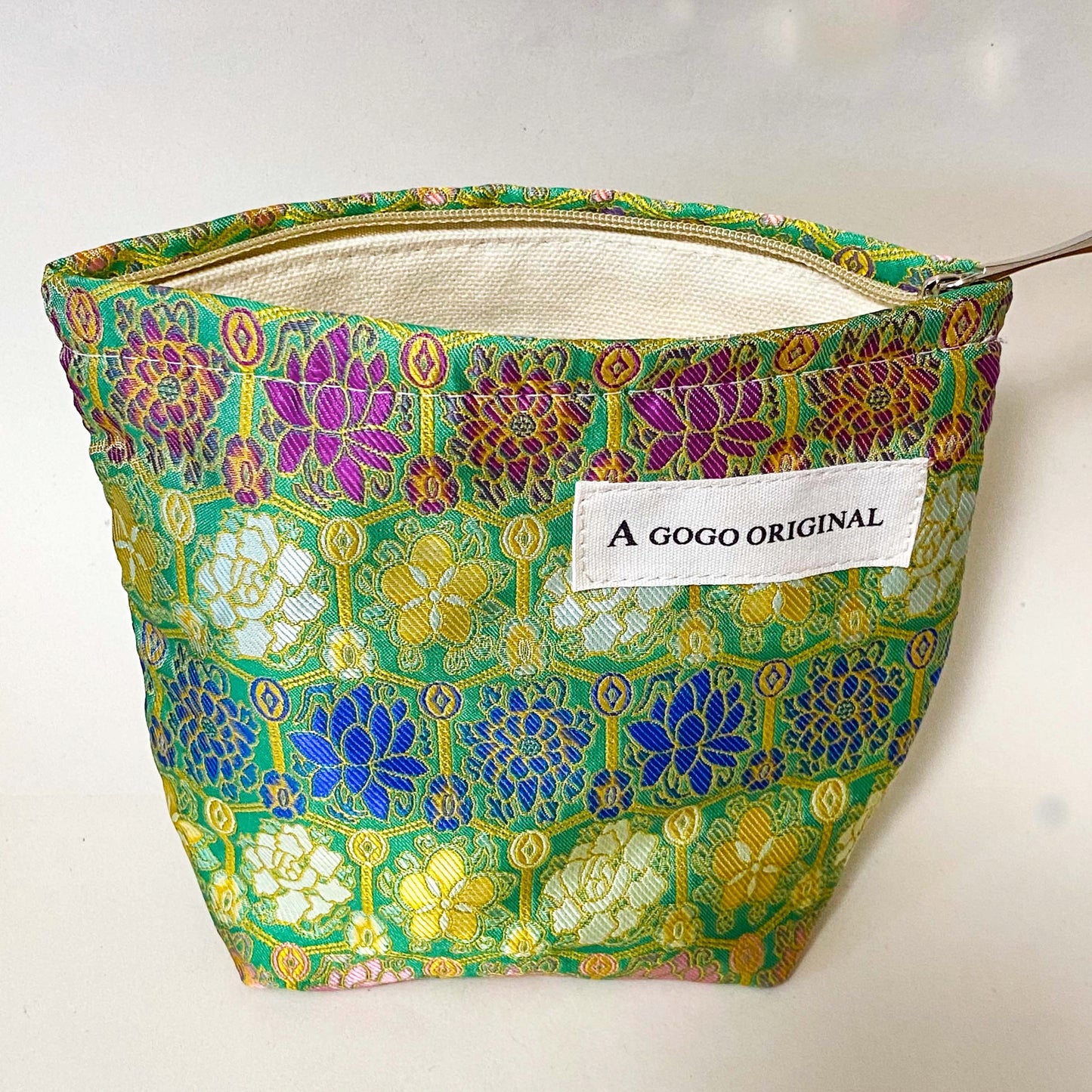 premium woven brocade cosmetic pouch in jade green with intricate mosaic inspired pattern in blue, purple, antique gold and cream. Fully lined with concealed zip. UK letterbox gifts shop. Small ornate fabric make up bag. 