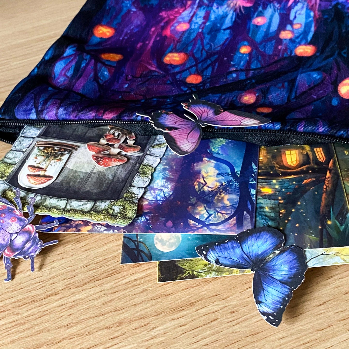 close up of moonlit forest pouch with glowing lantern trees, butterfly sticker and illustrated woodland postcards