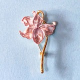pale pink iris enamel and metal brooch on gold tone with a blue background