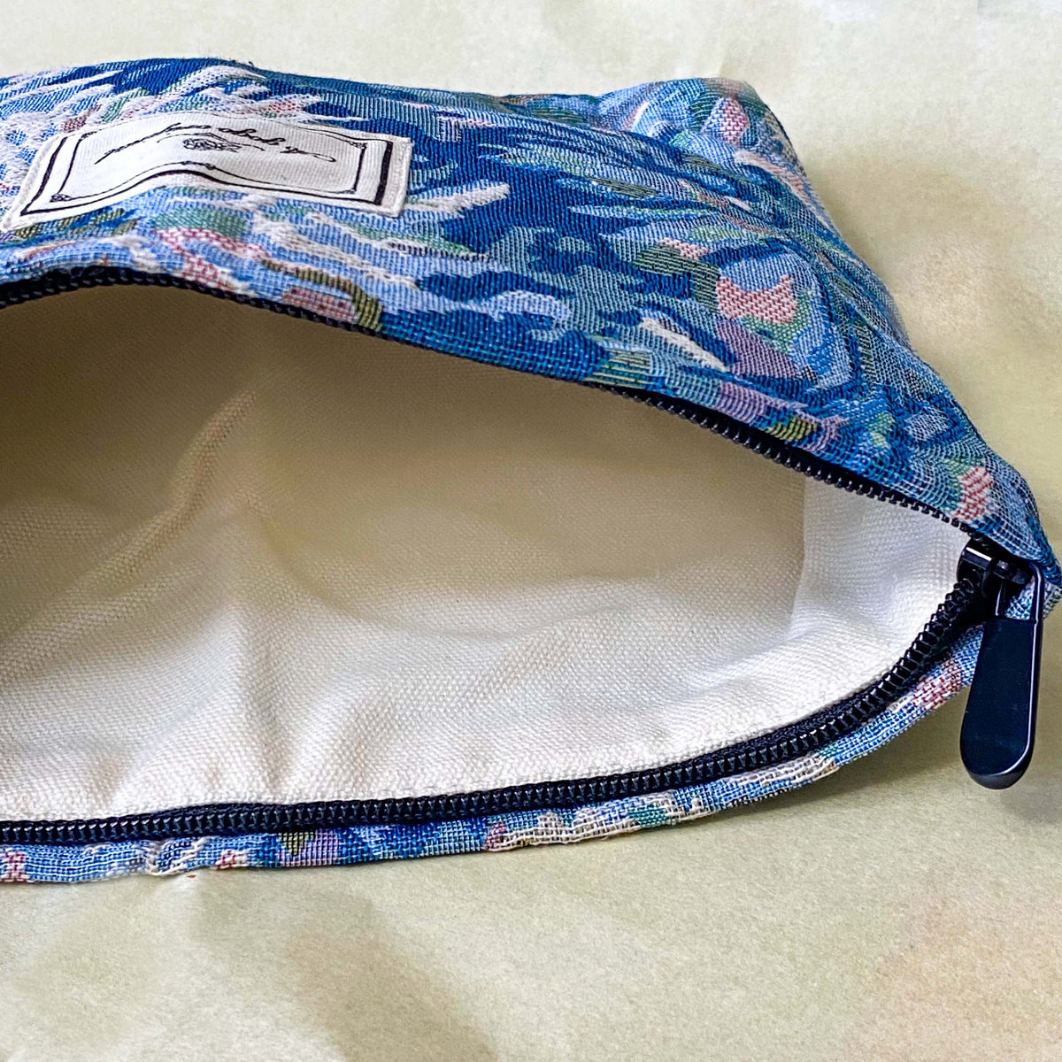 blue, pale pink and turquoise chrysanthemum tapestry pouch with woven floral fabric, cream lining, concealed zip closure and gusseted base. Botanical make up cosmetic pouch, large pencil case or journaling bag. Uk gifts shop. Gifts for flower lovers.
