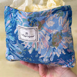 blue, pale pink and turquoise chrysanthemum tapestry pouch with woven floral fabric, cream lining, concealed zip closure and gusseted base. Botanical make up cosmetic pouch, large pencil case or journaling bag. Uk gifts shop. Gifts for flower lovers.