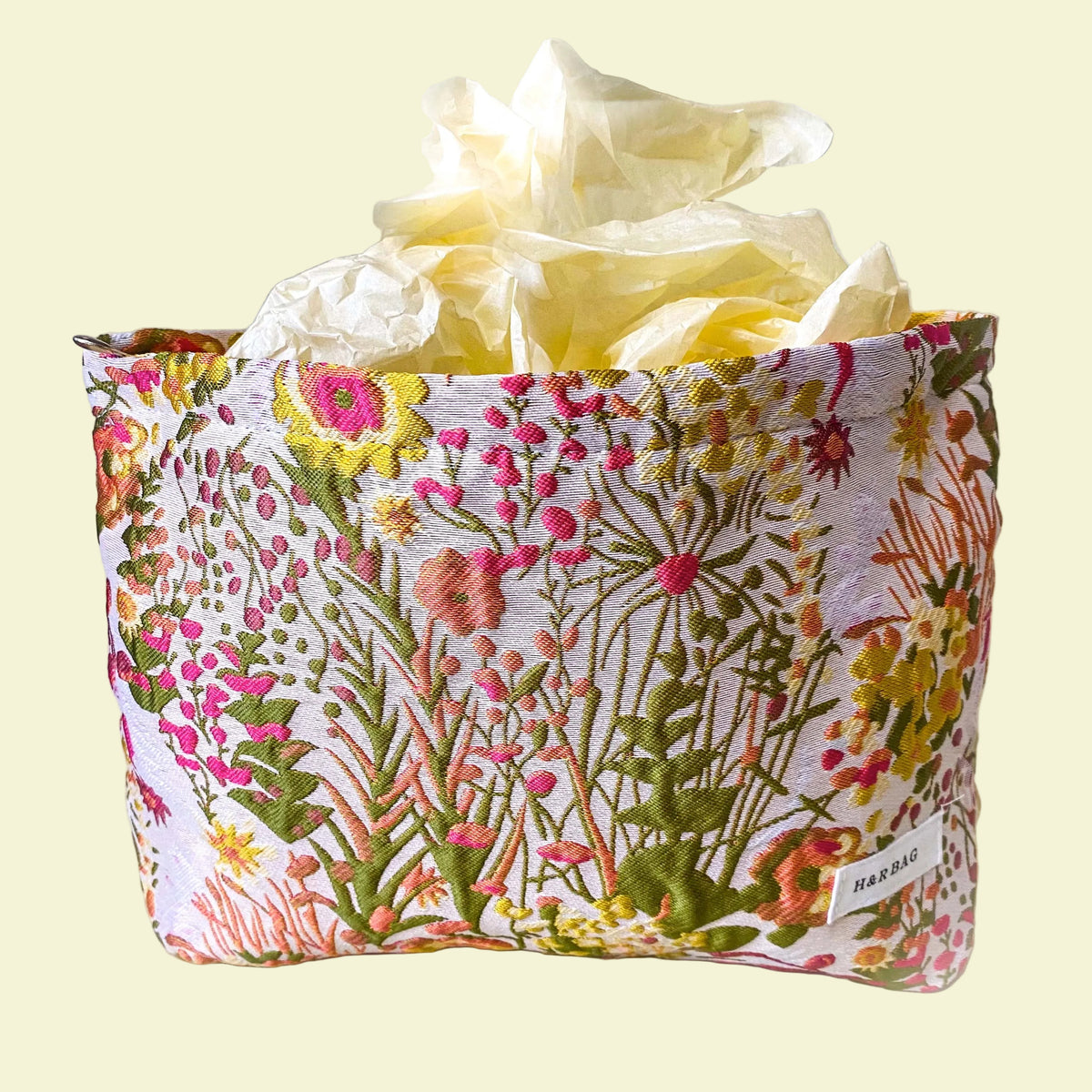 wildflower meadow tapestry pouch with colourful woven floral design including daisies, cream lining, concealed zip closure and gusseted base. Cream, orange, lemon, soft green and white design. Subtle sheen. Large cosmetic bag or toiletry pouch. Uk botanical gift shop.