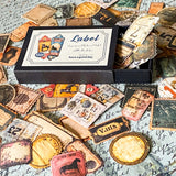 close up of vintage label stickers in a mini black box, labels have antique paper designs including tickets and packaging tags