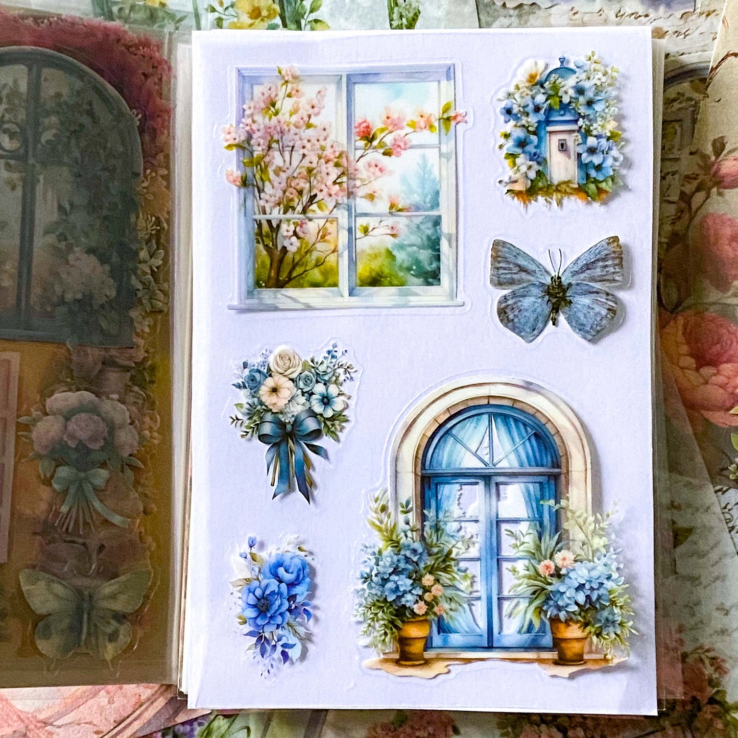 close up of blue floral and butterfly stickers and window details on a clear plastic PET sheet