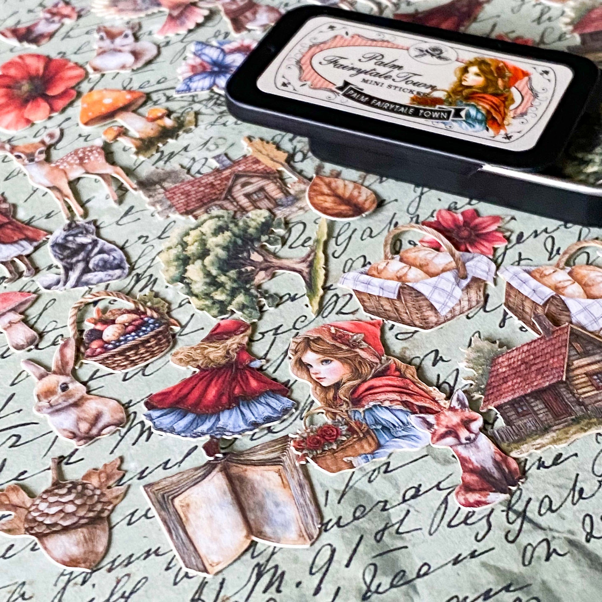 mini metal tin with card stickers in a red riding hood storybook theme including cloaked girl, fox, rabbit, wolf, cottage and deer in vintage style