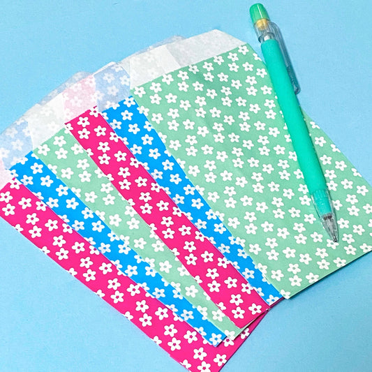 small paper bags with daisy print in cerise pink mint and blue on a blue backgound