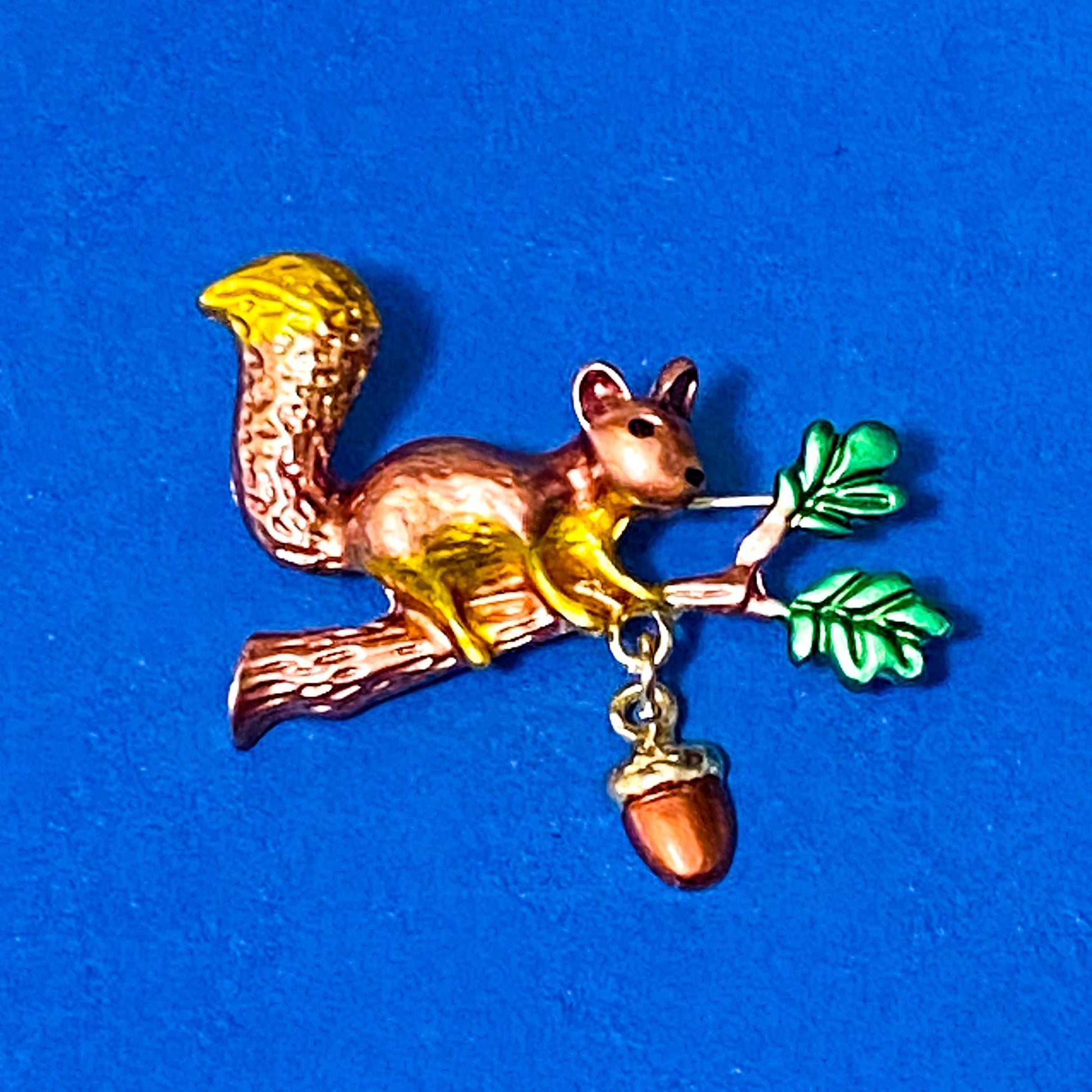 Squirrel brooch with acorn on a blue background