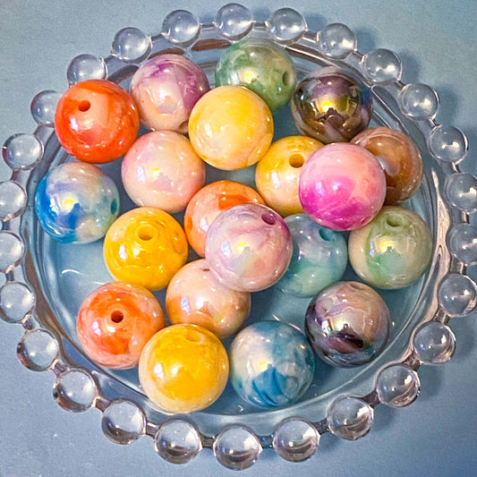 Colorful marbled 16mm acrylic beads in a decorative glass dish on a blue background