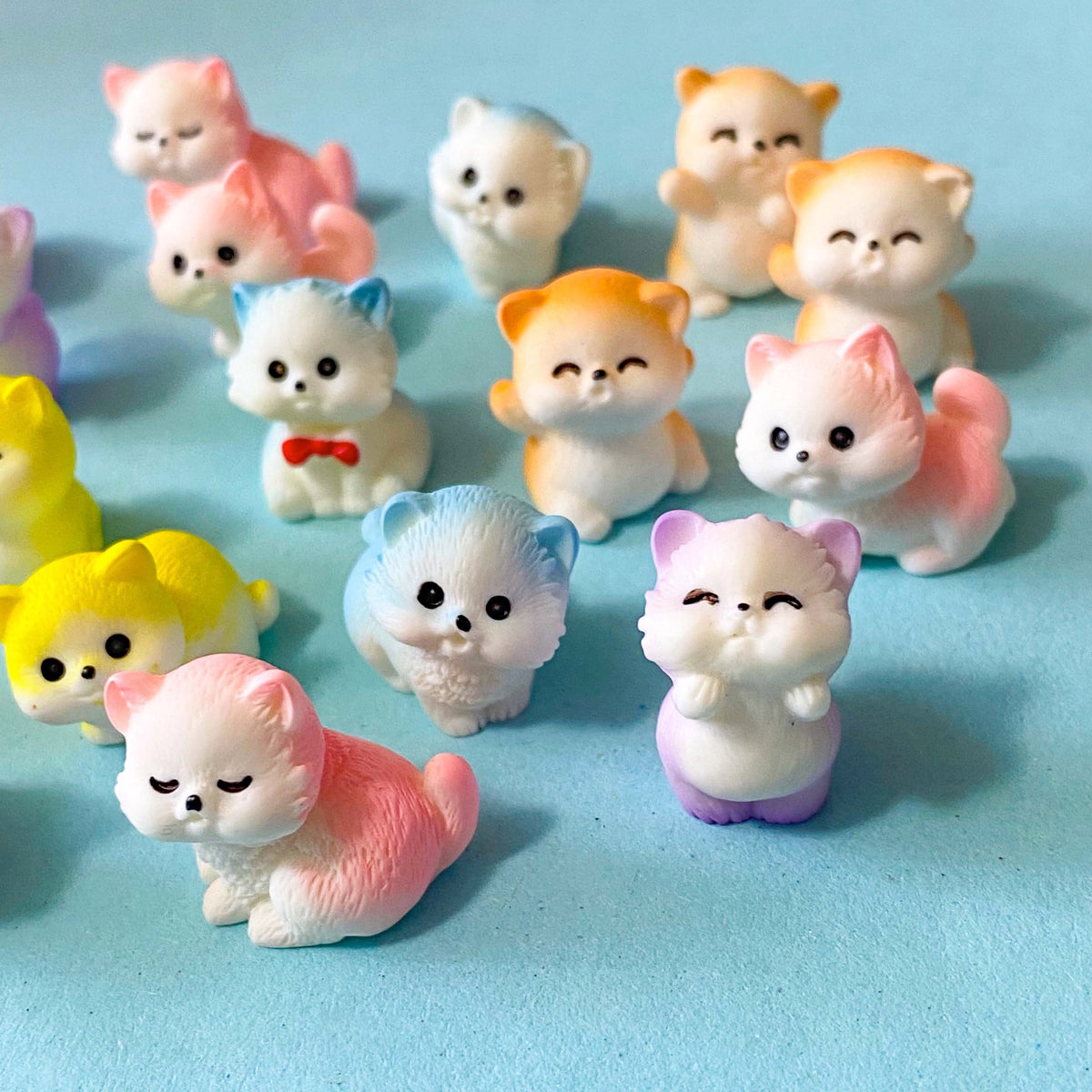 selection of miniature resin pastel kitten figurines in pink, lilac, blue, yellow and peach colours displayed on a pale blue background