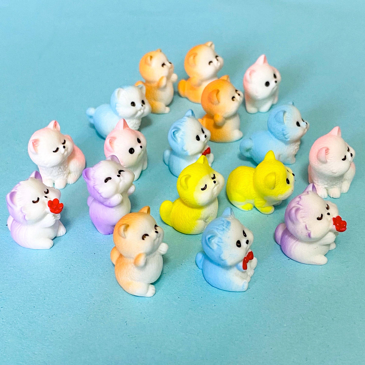 selection of miniature resin pastel kitten figurines in pink, lilac, blue, yellow and peach colours displayed on a pale blue background
