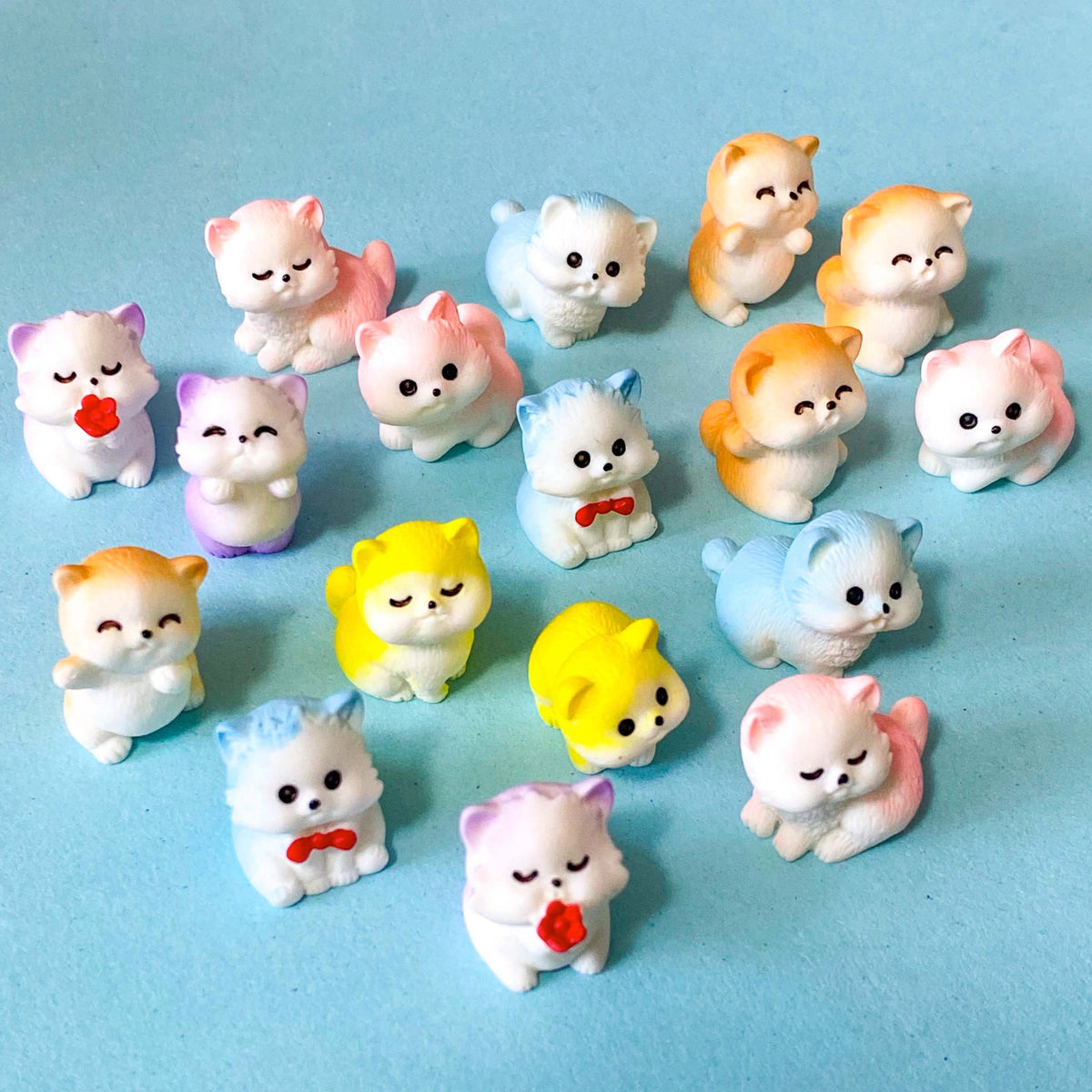 selection of miniature resin pastel kitten figurines in pink, lilac, blue, yellow and peach colours displayed on a pale blue background