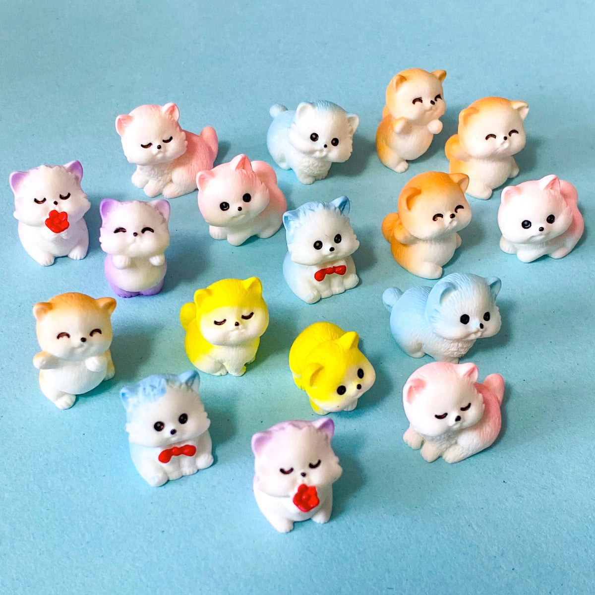 selection of miniature resin pastel kitten figurines in pink, lilac, blue, yellow and peach colours displayed on a pale blue background