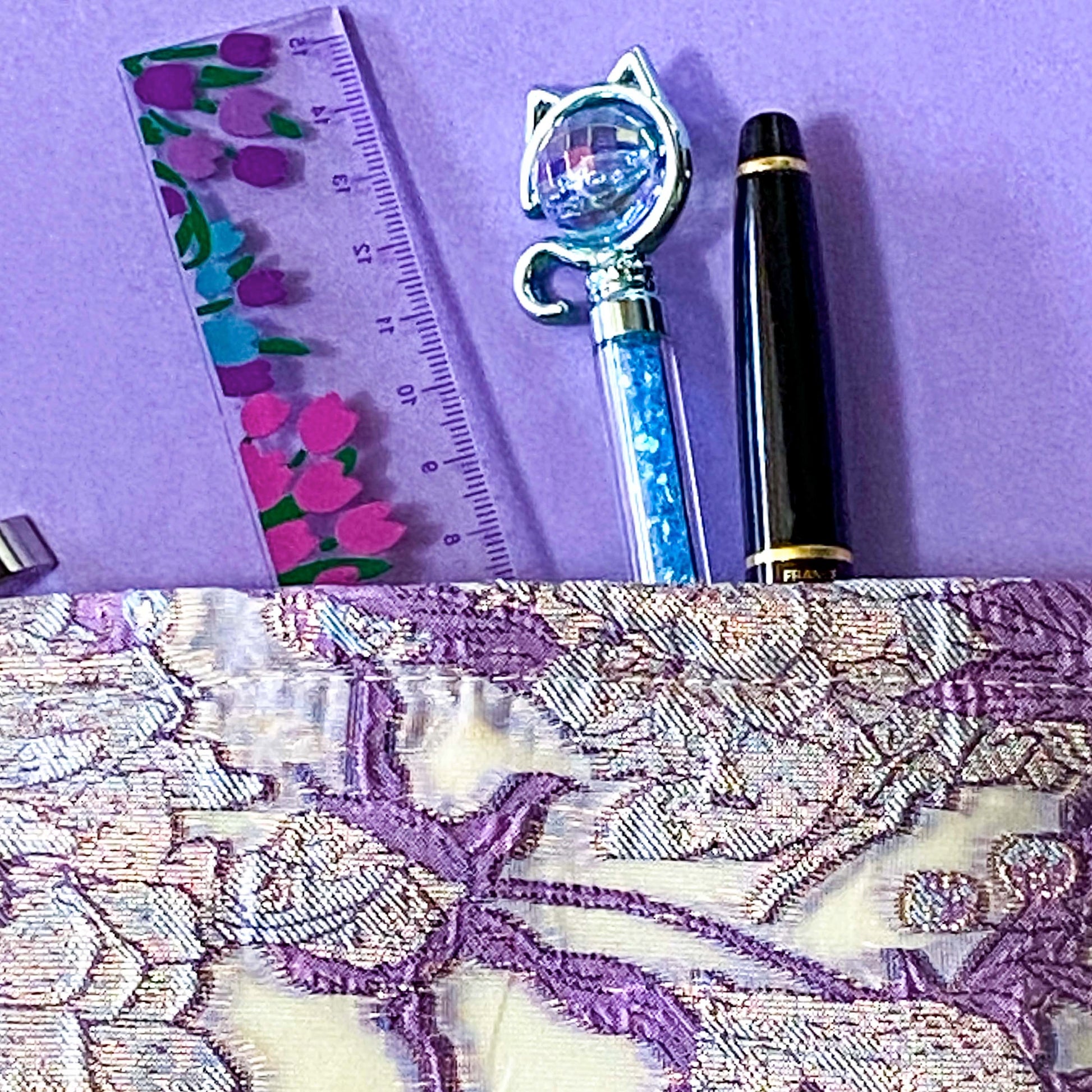 wisteria veil luxury woven tapestry cosmetic pouch with an ivory background and lavender and lilac botanical design, shimmering pale pink-lilac metallic threads, cream fabric lining and concealed zip.