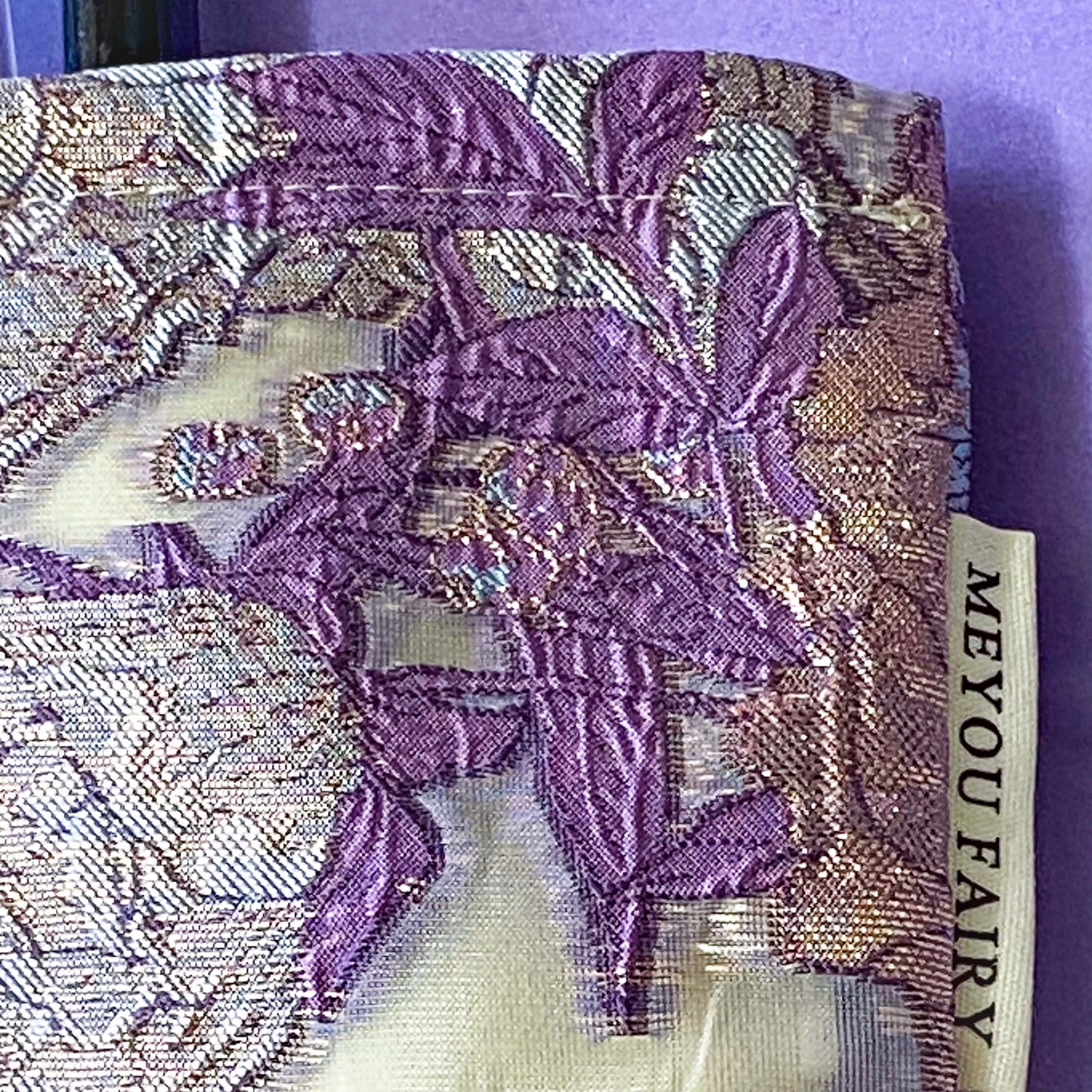 wisteria veil luxury woven tapestry cosmetic pouch with an ivory background and lavender and lilac botanical design, shimmering pale pink-lilac metallic threads, cream fabric lining and concealed zip.