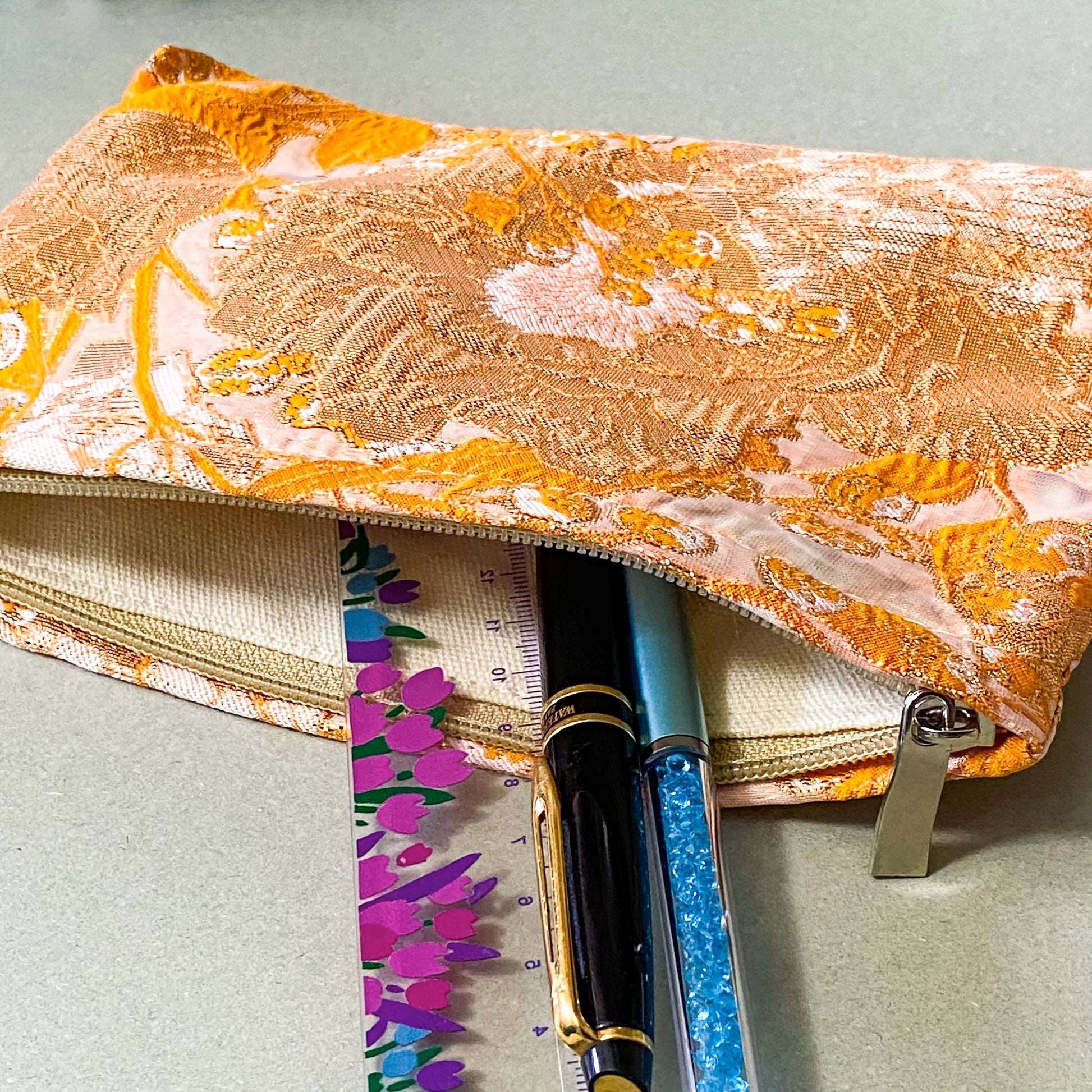 peaches and cream warm orange and gold metallic thread woven tapestry pouch for make up and beauty essentials. fully lined in cream with a concealed zip. floral pattern small fabric cosmetic bag. uk letterbox gifts.