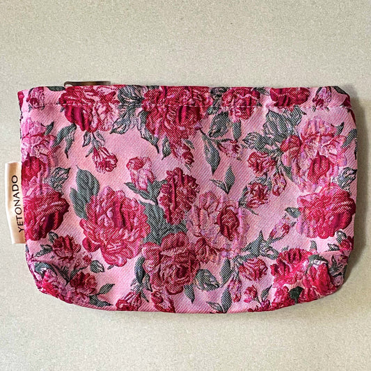 vintage rose arbour textured woven fabric tapestry make up pouch in smaller size with pink and red roses on pale pink background with soft green leaves. fully lined in cream fabric with concealed zip and gusset for space. uk letterbox gifts.