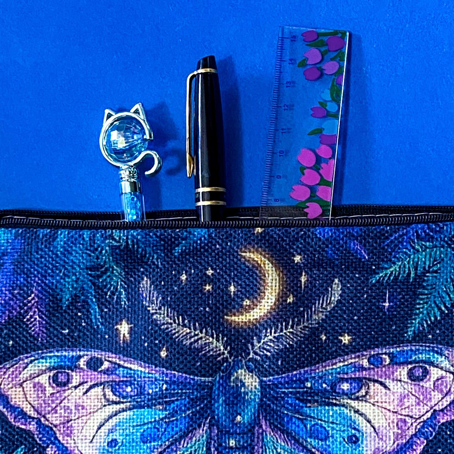 dark blue canvas zip pouch featuring a colourful luna moth beneath a crescent moon with stars and woodland ferns. Shades of lilac, purple, teal and blue. Pencil case or make up bag.