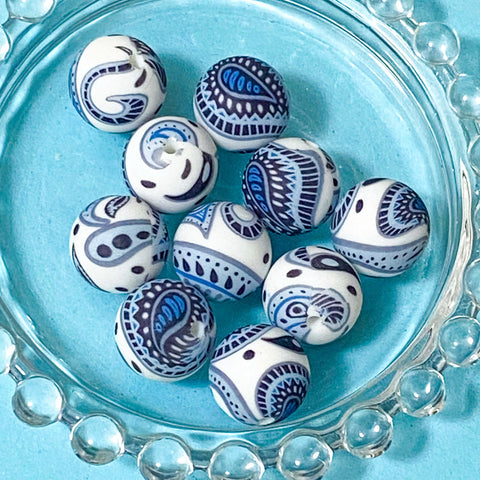 dark blue and white patterned paisley silicone beads on a blue background