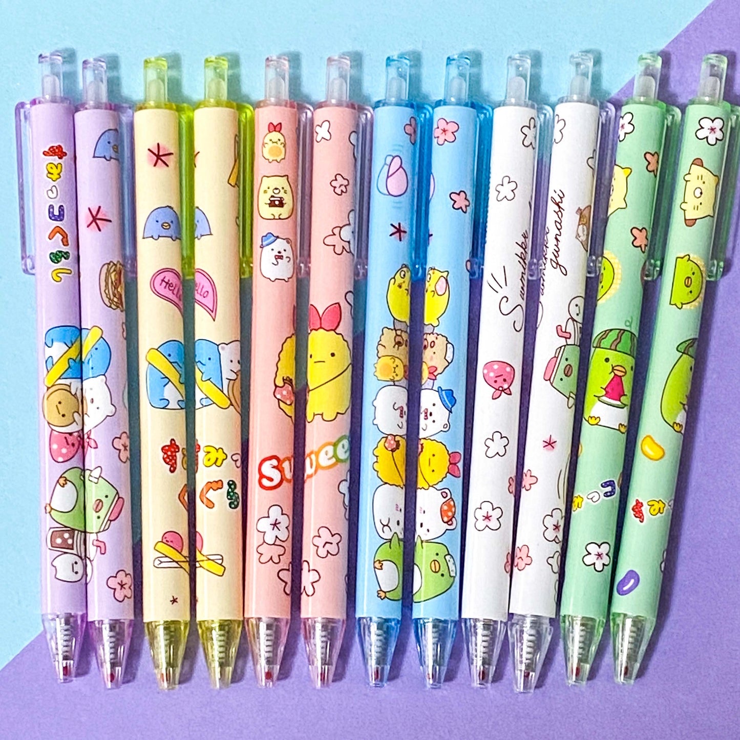 Set of colorful pens with cartoon character designs on a blue and purple gradient background