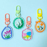 Set of colourful acrylic keychains with floral designs on a light blue background