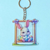 Keychain with a cartoon bunny on a swing against a light blue background