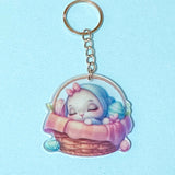 Keychain with a cute spring bunny acrylic charm in a basket on a light blue 